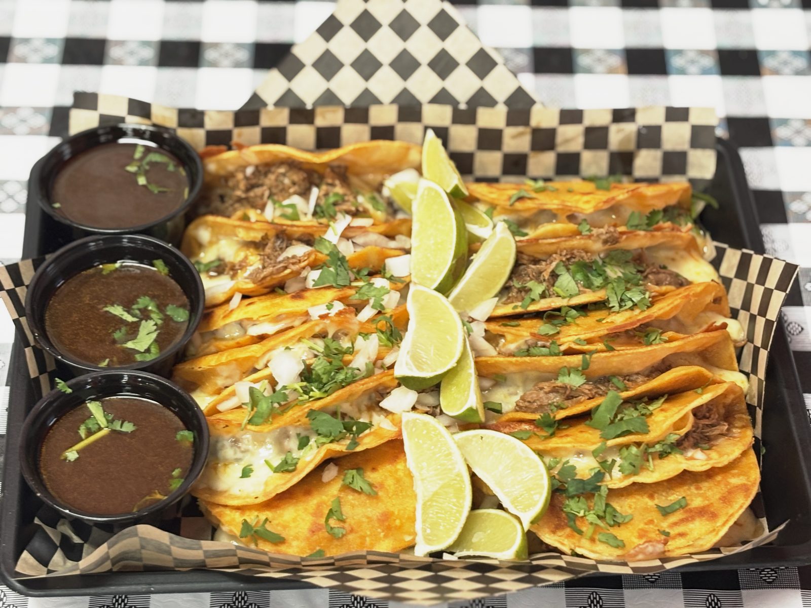 Family pack of 12 birria tacos with salsa, cilantro, onions, and limes